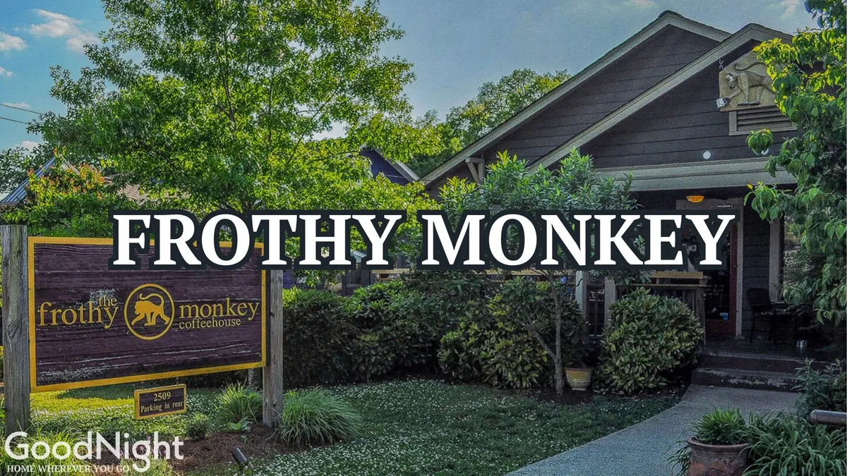 The image presents the inviting exterior of 'Frothy Monkey,' a popular Nashville coffee shop, surrounded by greenery. People can be seen working or socializing, creating a relaxed yet productive atmosphere perfect for remote work or informal meetings.