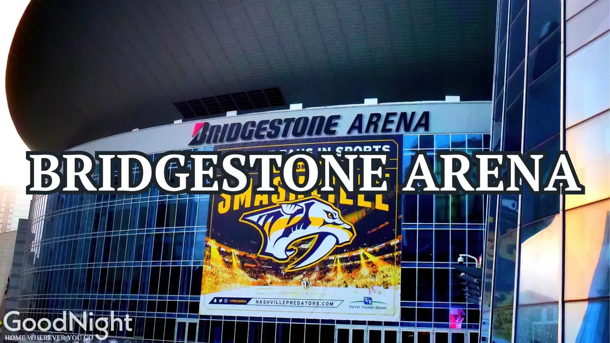 A vibrant street-level view of Bridgestone Arena, with the Nashville Predators banner prominent above the modern glass facade. People are gathered outside, reinforcing the arena as a lively hub for sports and concerts.