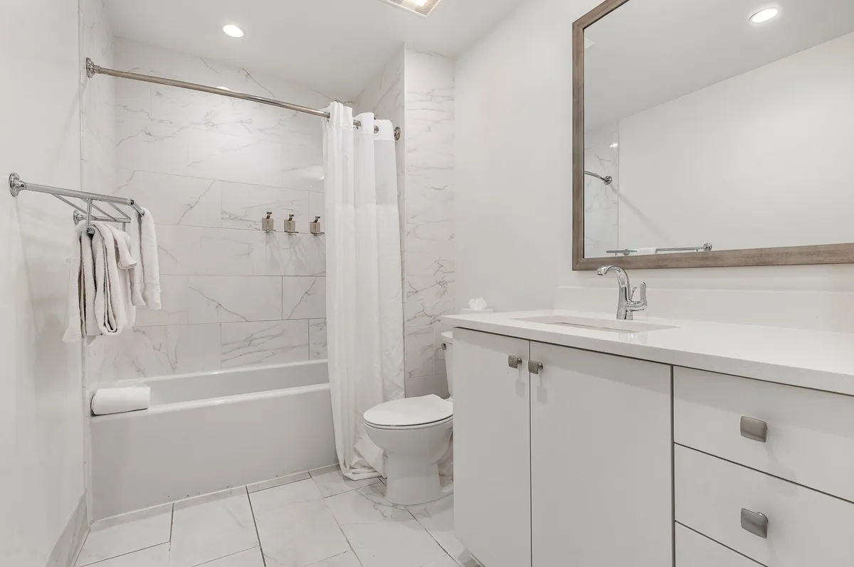 This image features a serene bathroom with a bathtub, vanity, and mirror. The calm ambiance and clean design suggest a space perfect for both energizing morning routines and relaxing evening soaks. Fresh towels are visible, reinforcing the spa-like experience described in the section.